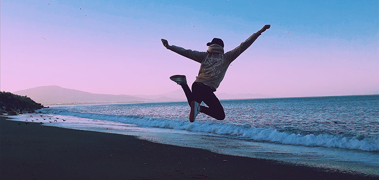 man jumping on beach at dusk Celebrating the benefits of meditation
